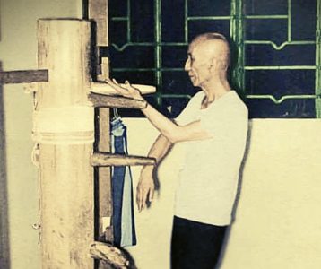 A Wing Chun practitioner demonstrating Kwan Sao on the wooden dummy